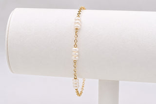 Pearl bracelet on a white cylindrical stand with a gray background
