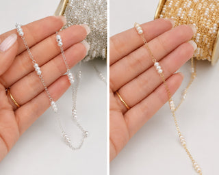 Two pearl necklaces, one silver and one gold, held in hands against a neutral background.